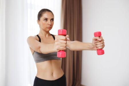 Beautiful fitness girl make sport execises. Focus on hands holding dumbells.の写真素材