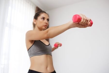 Beautiful fitness girl make sport execises. Focus on hand holding dumbell.
