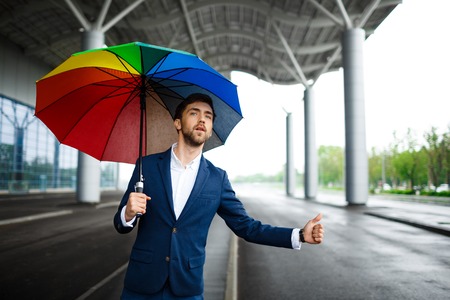 Picture of  young businessman holding motley umbrella and catching the carの写真素材