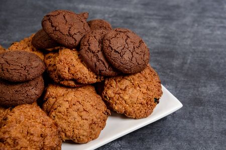 Sweet oatmeal and chocolate cookies on wooden table