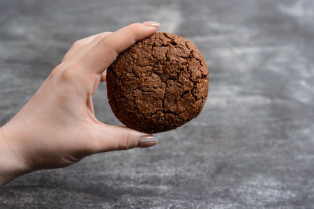 Picture of hands hold chocolate cookies over wooden backgroundの写真素材