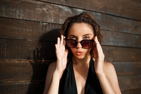 Beautiful young  cheerful girl dressed in swimwear and wearing glasses rest on beachの写真素材