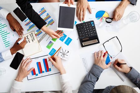 Picture of businessmen's hands on white table with documents, coffee and draftsの写真素材