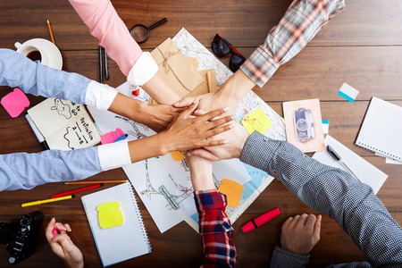 Picture of businessmen's hands on wooden table with documents, coffee and draftsの写真素材