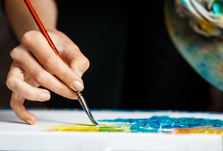 Close up photo of girl drawing with oil paints on canvas. Copy space.の写真素材