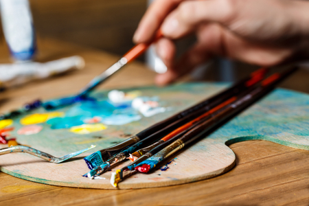 Close up photo of girl mixing oil paints on palette. Copy space. Focus on brushes.の写真素材
