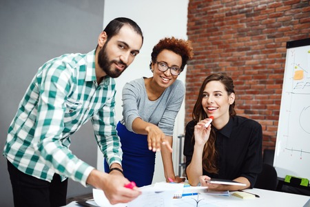 Colleagues speaking, smiling, discussing new ideas at business meeting.の写真素材