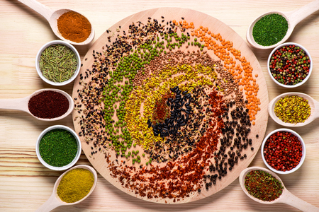 Colorful spices on wooden board and in spoonsの写真素材