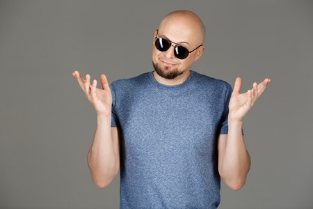 Portrait of confident handsome middle-aged man in grey shirt and sunglasses posing over dark background. Copy space.の写真素材