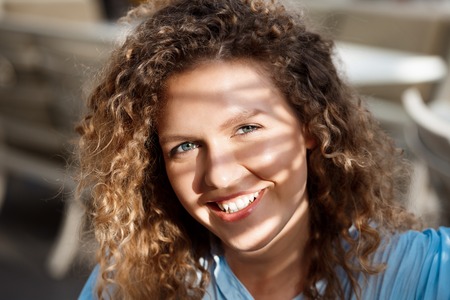 Young beautiful girl smiling, looking at camera, sitting in cafe.