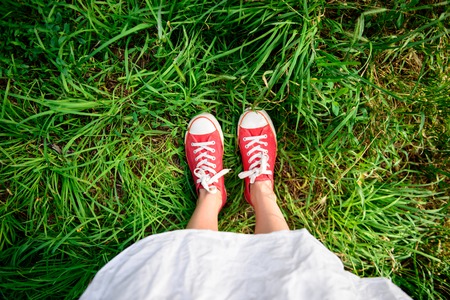 Close up photo of girl's legs in red keds on grass. Copy space.の写真素材