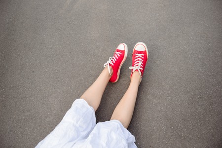 Close up photo of girl's legs in red keds lying on asphalt. Copy space.の写真素材