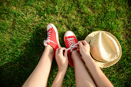 Close up photo of girl's legs in red keds lying on grass. Copy space.の写真素材