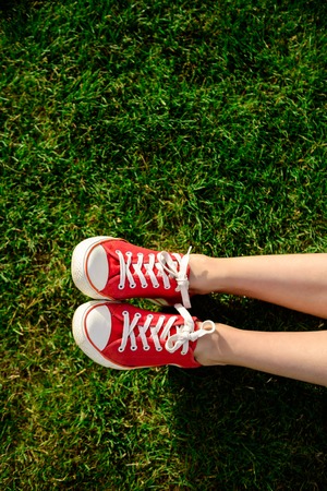 Close up photo of girl's legs in red keds lying on grass. Copy space.の写真素材