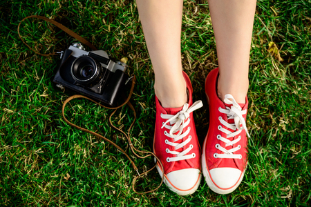 Close up photo of girl's legs in red keds lying on grass. Copy space.の写真素材