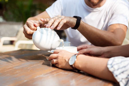 Young beautiful couple speaking, smiling, drinking tea, resting, sitting in cafeの写真素材