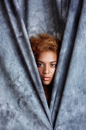 Young beautiful african girl looking at camera, posing, wrapping up  in grey cloth. Copy space.の写真素材