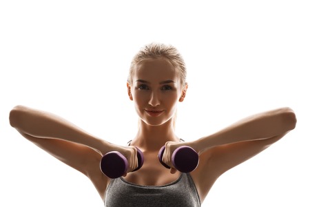 Young beautiful sportive girl training with dumbbells over white background. Copy space.