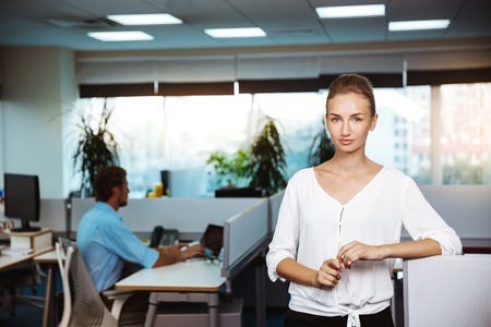 Young beautiful successful businesswoman smiling, posing, office backgroundの写真素材