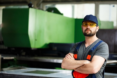 Portrait of worker in overalls with crossed arms, industrial steel factory background.の写真素材
