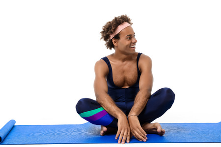 Young handsome sportive african man smiling, sitting on  karemat over white background. Copy space.の写真素材