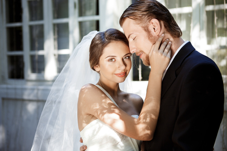 Young beautiful newlyweds in suit and wedding dress smiling, enjoying, embracing. Copy space.の写真素材