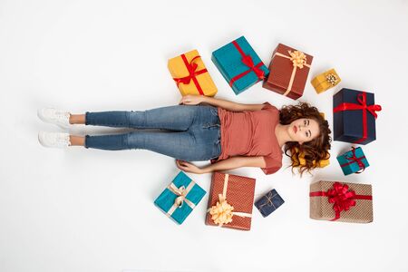 Young beautiful curly girl lying on floor among gift boxes Shot from above Isolated Copy spaceの写真素材