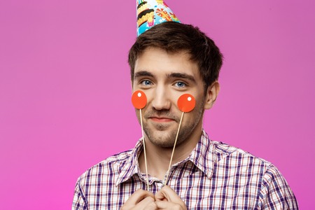 Young handsome man celebrating birthday party over purple background. Copy space.