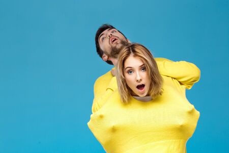 Young beautiful couple in one yellow sweater posing smiling having fun over blue background. Copy space.の写真素材