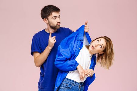Young beautiful couple posing having fun  over light pink background. Copy spaceの写真素材