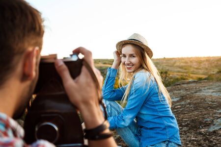 Handsome male photographer taking picture of his girlfriend, canyon background.の写真素材