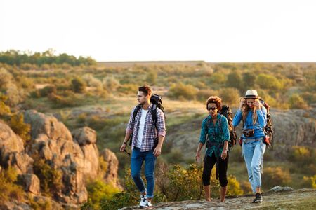 Young cheerful travelers with backpacks smiling, walking in canyon.の写真素材