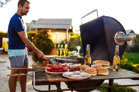 Young man roasting barbecue on grill in cottage countryside.の写真素材