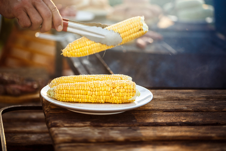 Young man roasting corn on grill.の写真素材