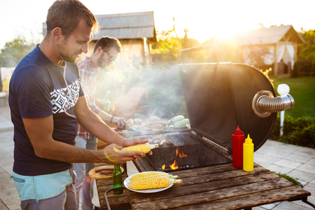 Young men roasting barbecue on grill in cottage countryside.の写真素材