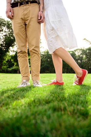 Close up of couples legs in keds on grass.の写真素材