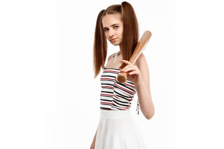 Young brutal pretty girl posing with bat, isolated on white background. Copy space.の写真素材