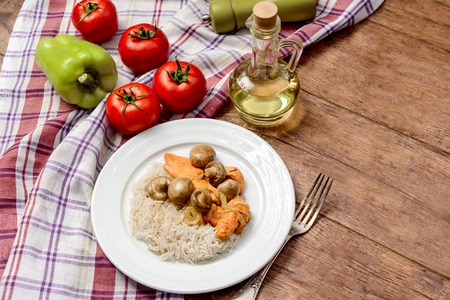 Rice, meat and mushrooms in a plate near oil and tomatoesの写真素材