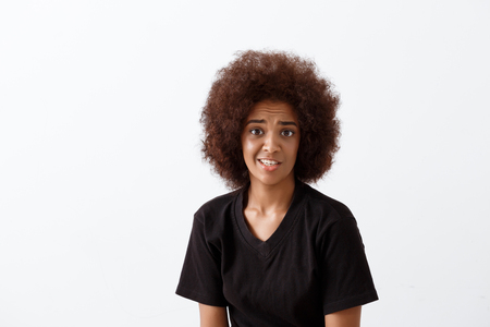 Young beautiful african girl smiling, looking at camera over light background. Copy space.の写真素材