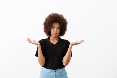 Upset young beautiful african girl looking at camera, gesturing over light background. Copy space.の写真素材