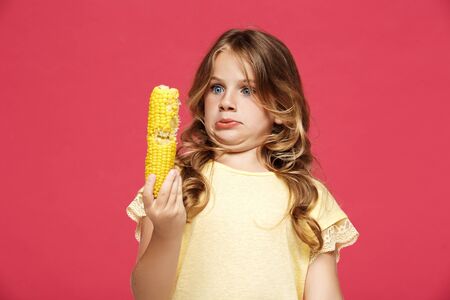 Young pretty girl holding corn,  over pink background. Copy space.