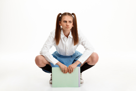 Young emotional pretty girl in uniform posing over white background.の写真素材