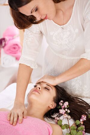 Sideview of young messeur doing facial massage on young womanの写真素材