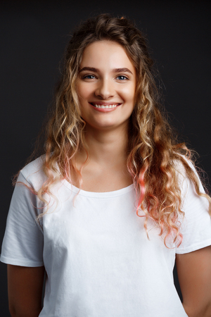 Young beautiful girl smiling, looking at camera over grey background.の写真素材