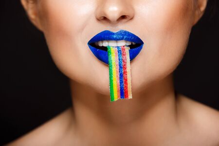 Closeup picture of sexy womans colorful lips holding sweeties.の写真素材