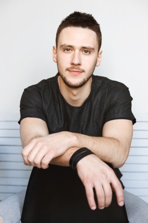 Closeup of guy relaxing, sitting on chair, looking straight.の写真素材