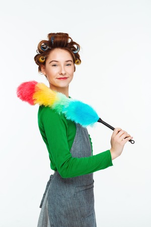 Charming woman posing while working with duster in handsの写真素材