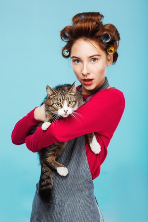 Beautiful girl with pretty cat in hands posing and looking to cameraの写真素材