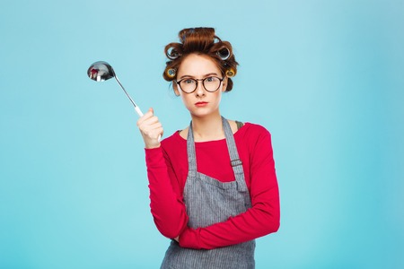 Nice funny girl hides from dangerous ladle and standing on blue background.の写真素材