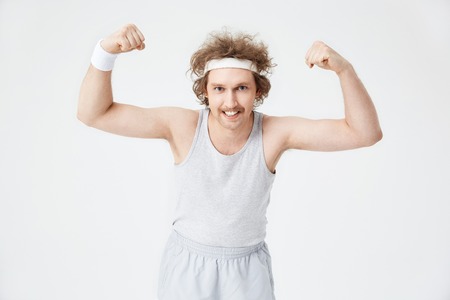 Funny man demonstrates biceps, showing teeth looking at cameraの写真素材